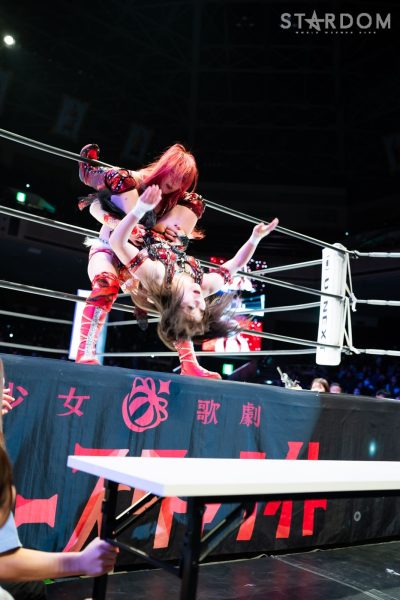 Suzu Suzuki attempts to catch Maika with a headscissors on the apron towards the table outside