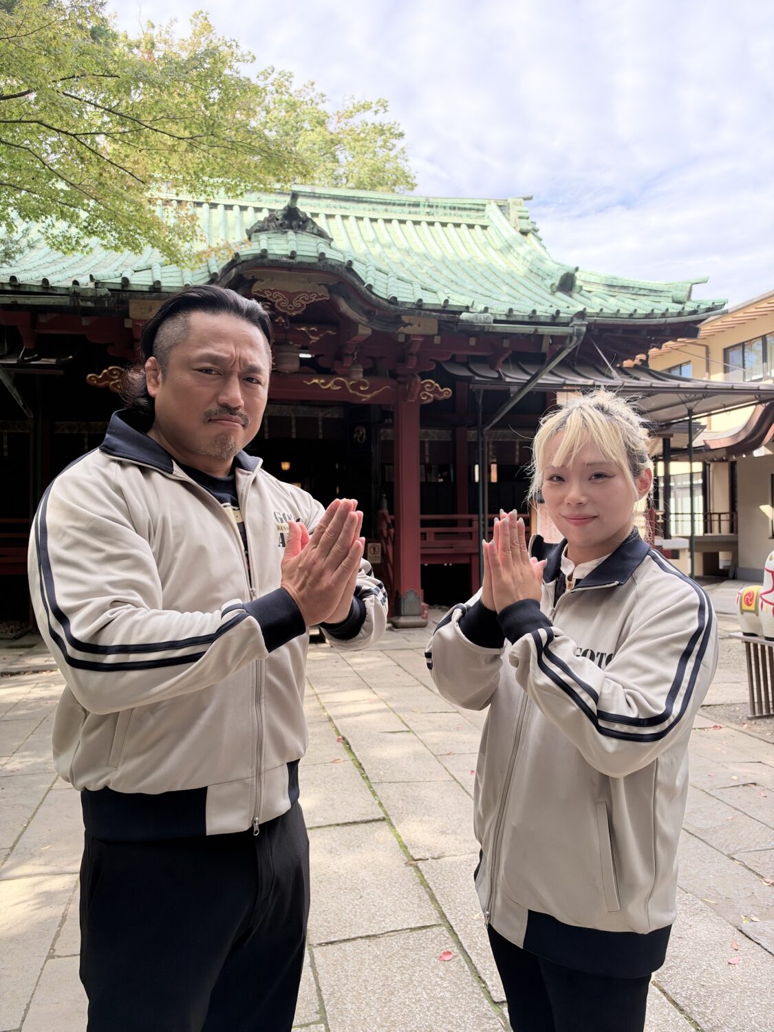 Hirooki Goto and Yuna Mizumori clasp their hands together in front of the main hall of Akasaka Hikawa Shrine
